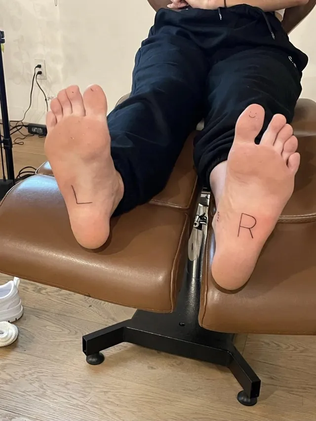 Charli D’Amelio showing bare soles while sitting in a chair.