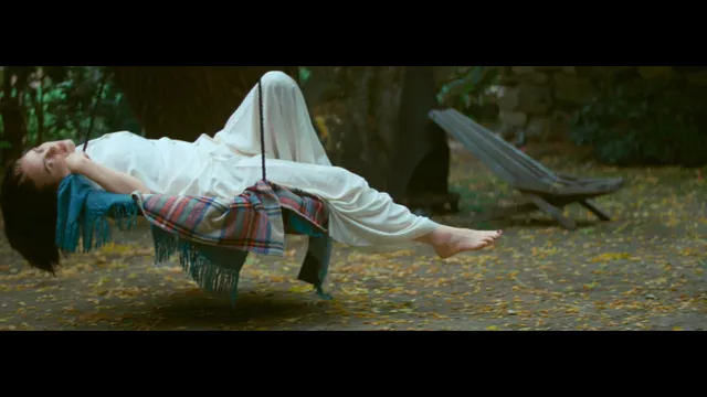 Billie Eilish a pale outfit while reclining on an outdoor swing.
