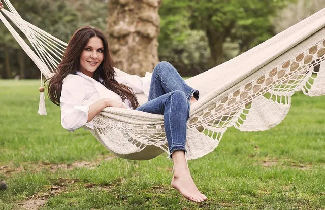 Catherine Zeta-Jones relaxing in a hammock outdoors in jeans.