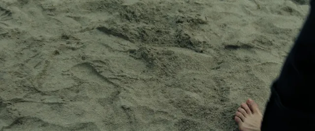 Anya Taylor-Joy showing a bare foot beside beach sand.