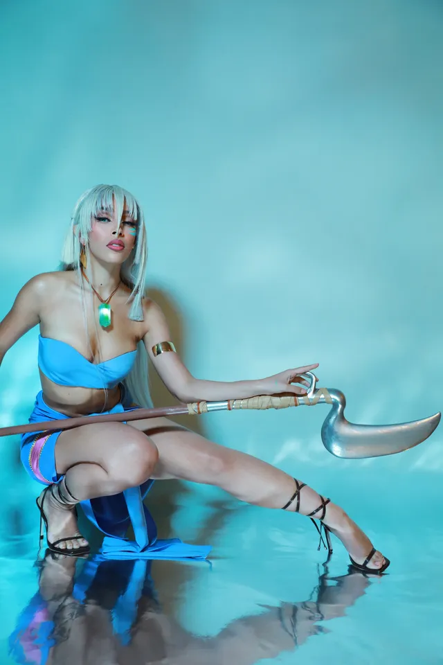 Doja Cat sitting in a blue outfit and black lace-up heels.