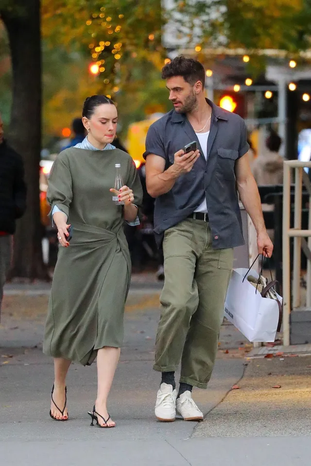 Daisy Ridley talking with a companion on a sidewalk.