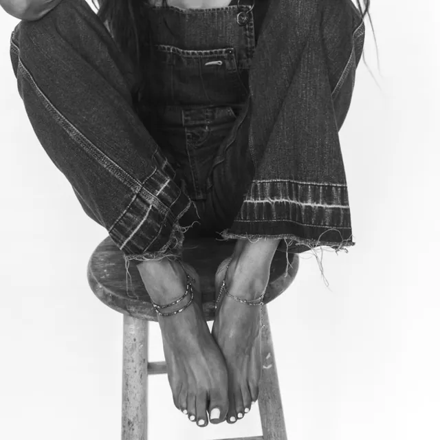 Sarah Shahi sitting on a stool for a black-and-white portrait.