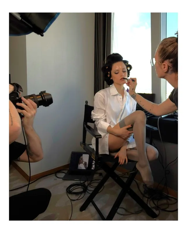 Jenna Ortega: seated barefoot while having her makeup prepared.