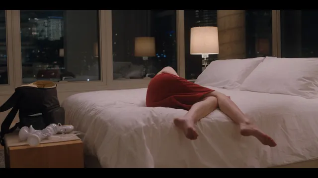 Anna Kendrick lying on a bed with bare feet hanging over the edge.