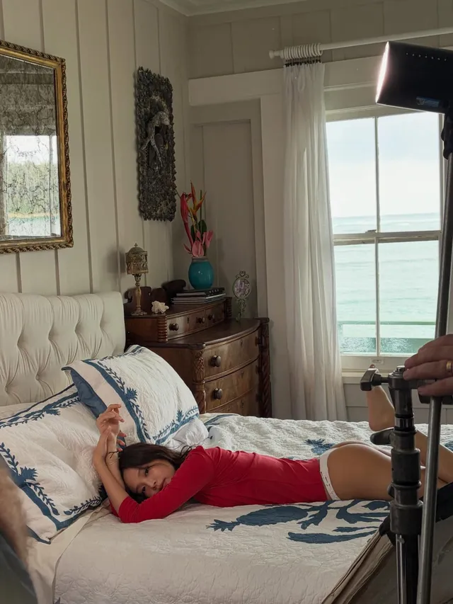 Jennie Kim lying barefoot on a bed in a red outfit.