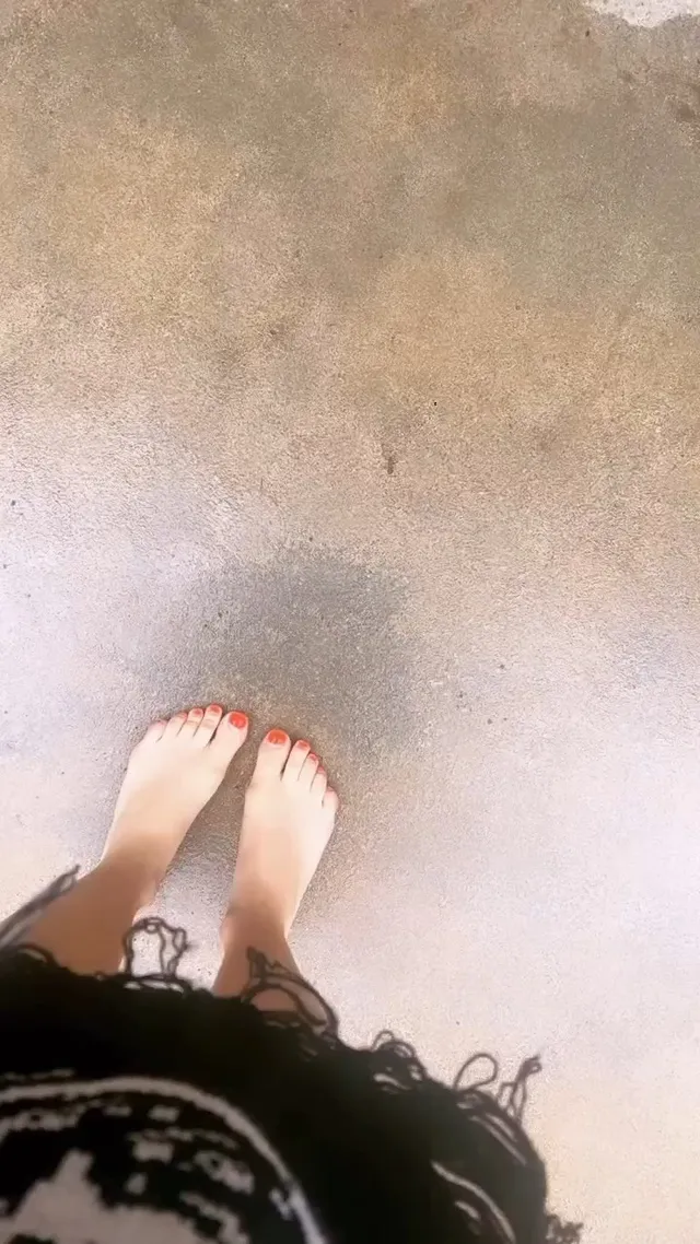Avril Lavigne standing barefoot on a pavement.