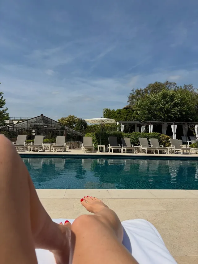 Alice Eve reclining beside a swimming pool.