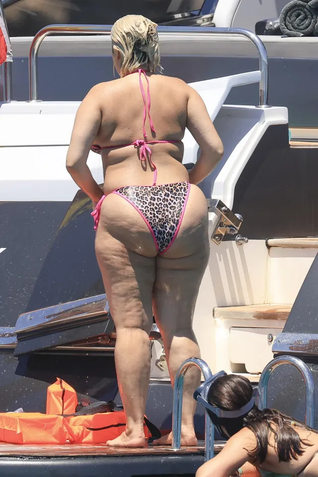 Bebe Rexha standing barefoot on a boat platform.