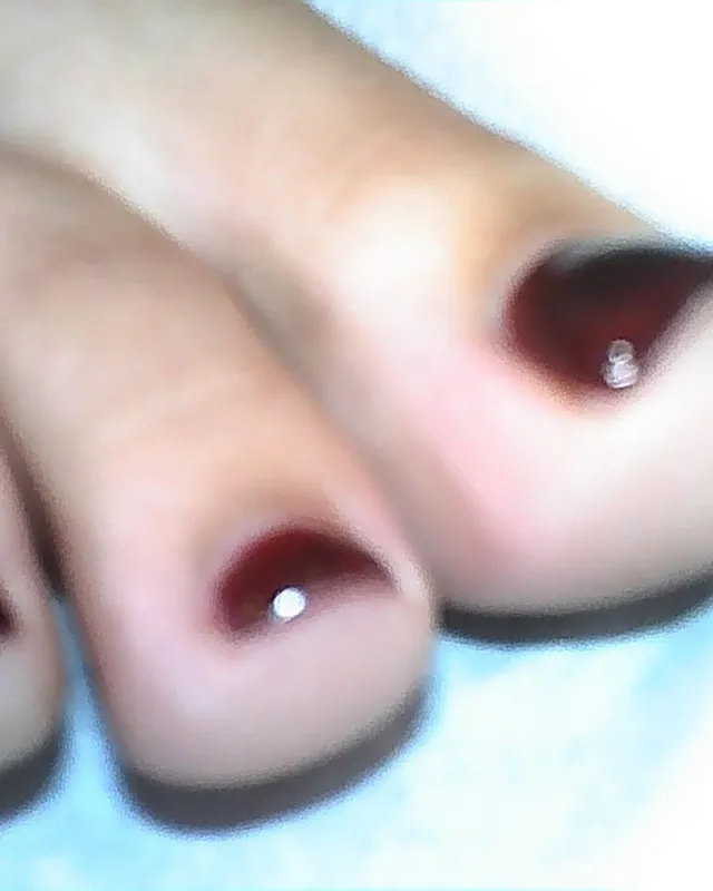 Doja Cat showing dark-painted toenails in a close-up photograph.
