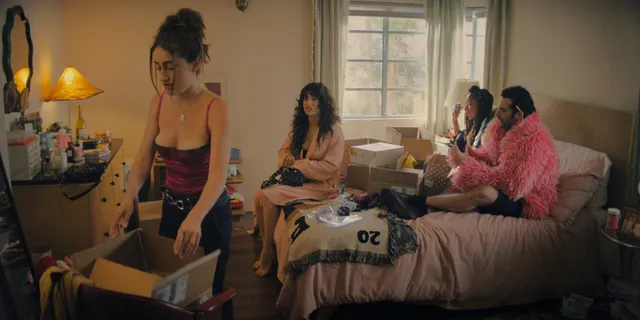 Odessa A'zion sitting on a bed with cast members in a scene.