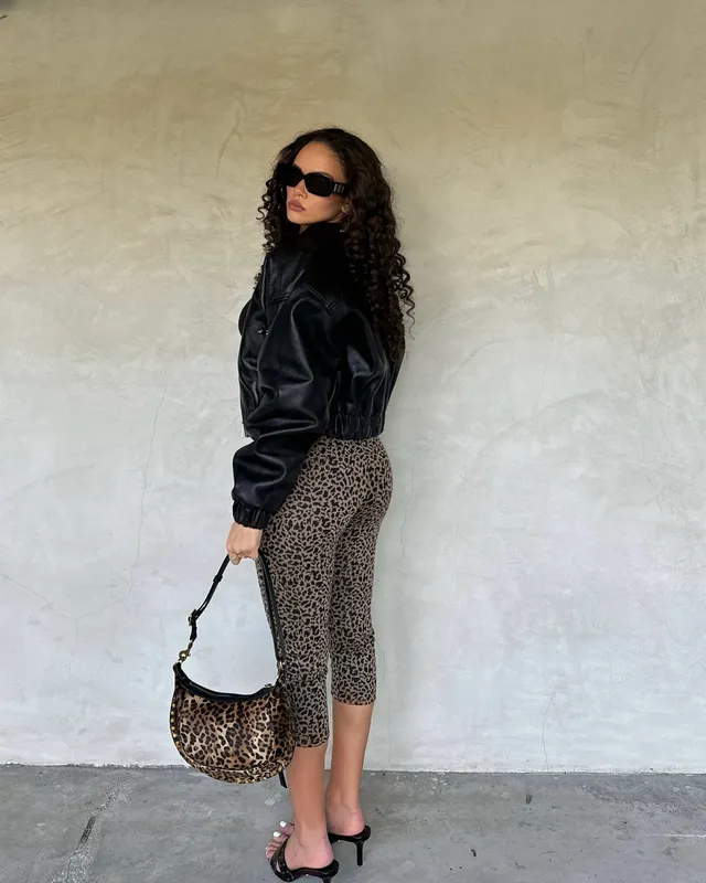 Madison Pettis posing in a black jacket, leopard-print skirt and black heels.
