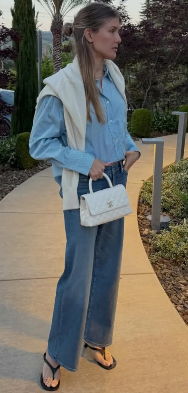 Eugenie Bouchard standing outdoors in flat sandals, jeans and a blue shirt.