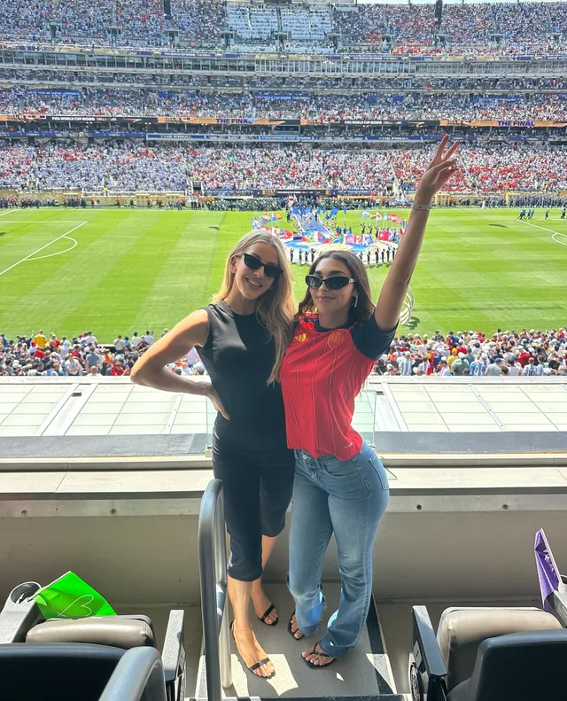Ellie Goulding posing beside another person at a sports stadium.