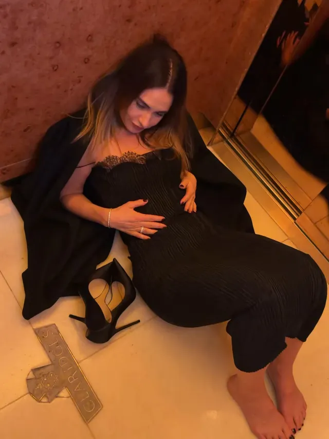 Lily James resting barefoot on a floor beside removed heels.