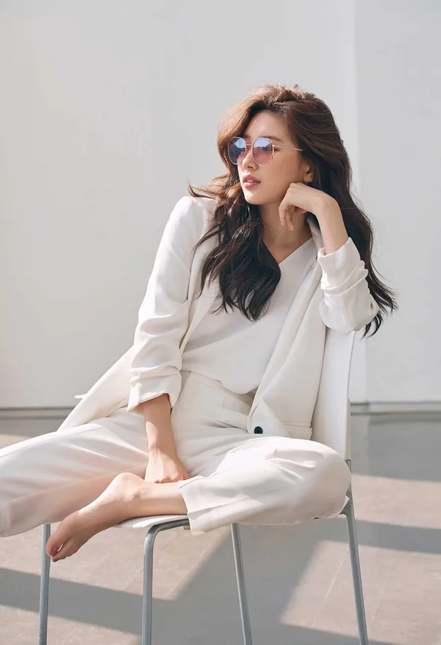 Bae Suzy sitting barefoot in a white suit and sunglasses.