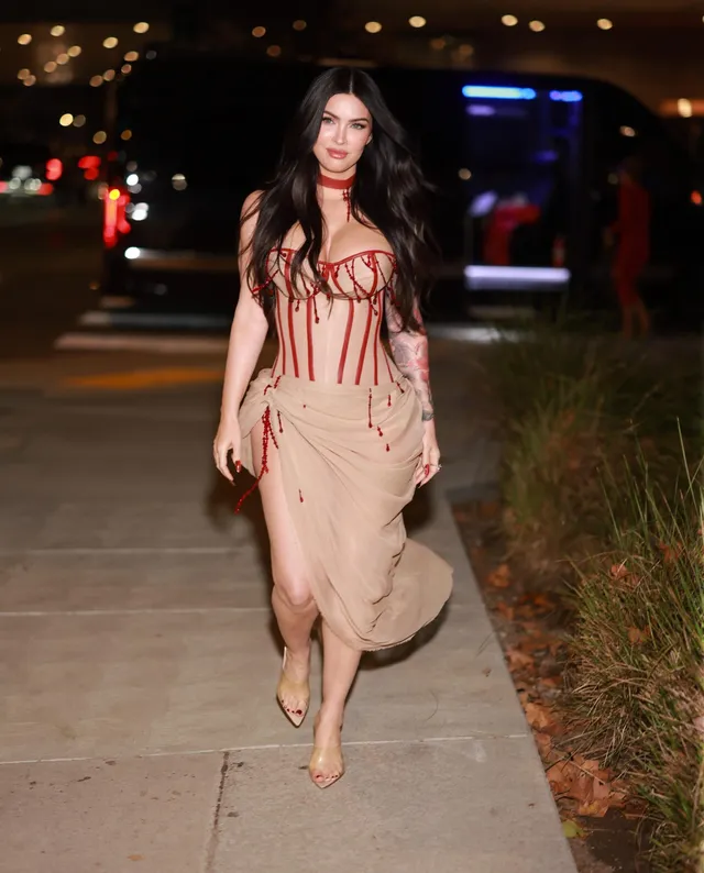 Megan Fox walking outside in a pale dress.
