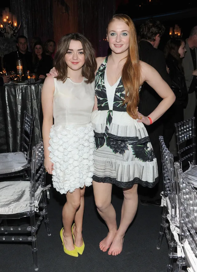 Sophie Turner standing at an evening event beside a friend.