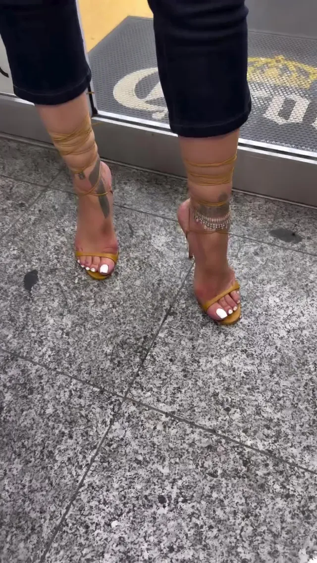 Rihanna wearing gold high-heeled sandals below cropped trousers.