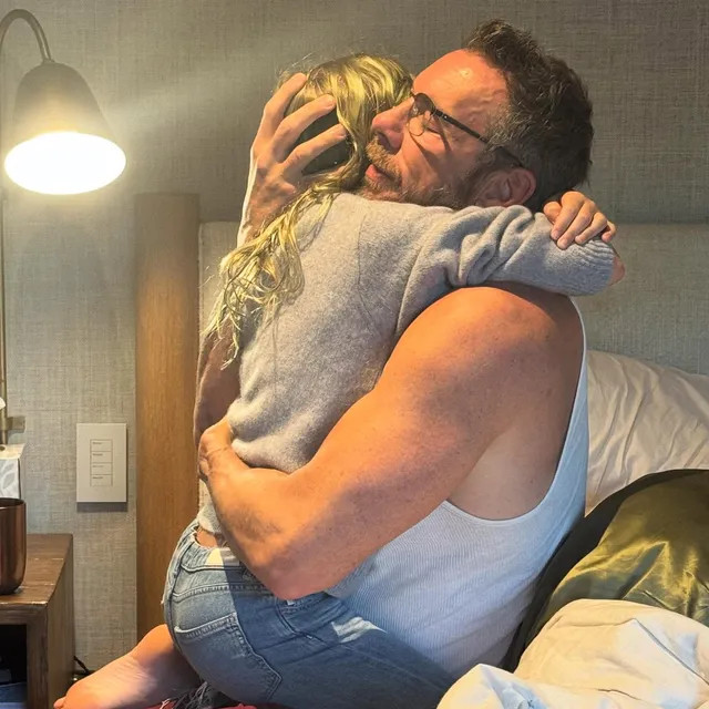 Kristen Bell being hugged while barefoot in a casual indoor photo.
