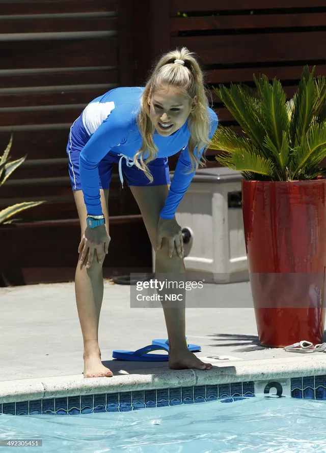 Anna Kournikova standing barefoot beside a swimming pool in a blue exercise outfit.