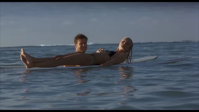 Kate Bosworth relaxing on a surfboard in the sea.