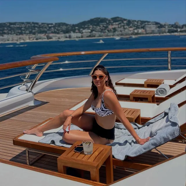 Alex Morgan sitting barefoot on a boat lounger overlooking the coast.