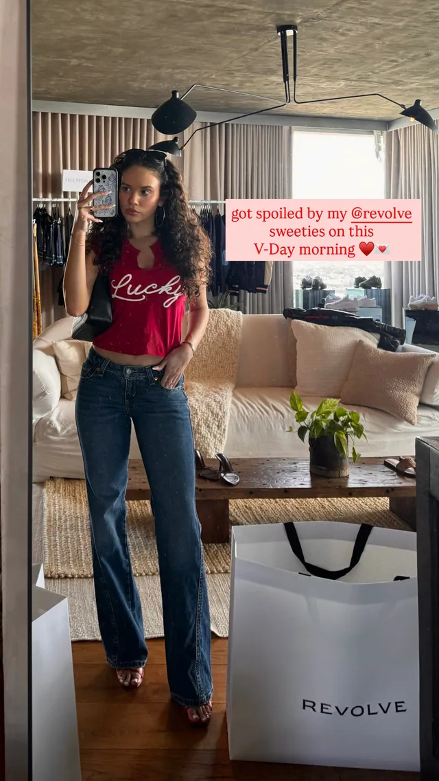 Madison Pettis posing indoors in a red top and jeans.