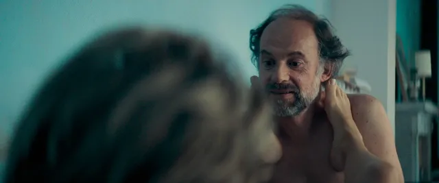 Léa Seydoux resting her bare feet beside a man in a screen scene.