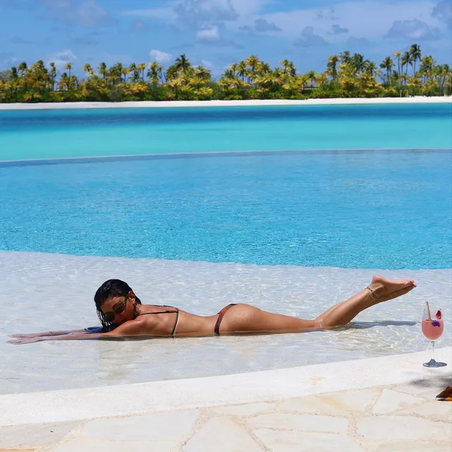 Sarah Hyland reclining beside an infinity pool.