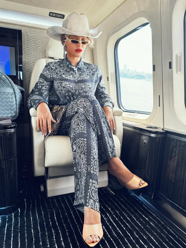 Beyoncé sitting aboard an aircraft in a patterned outfit and heels.