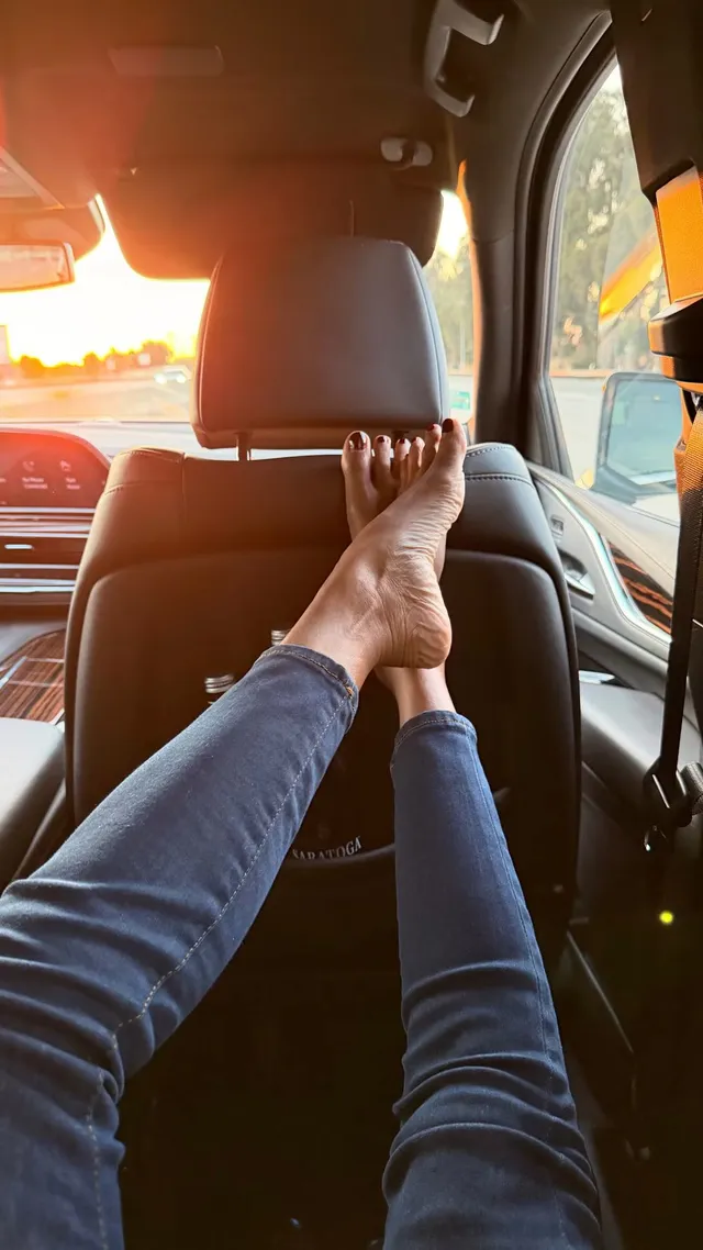 Zoe Saldaña resting her bare feet on a car seat.