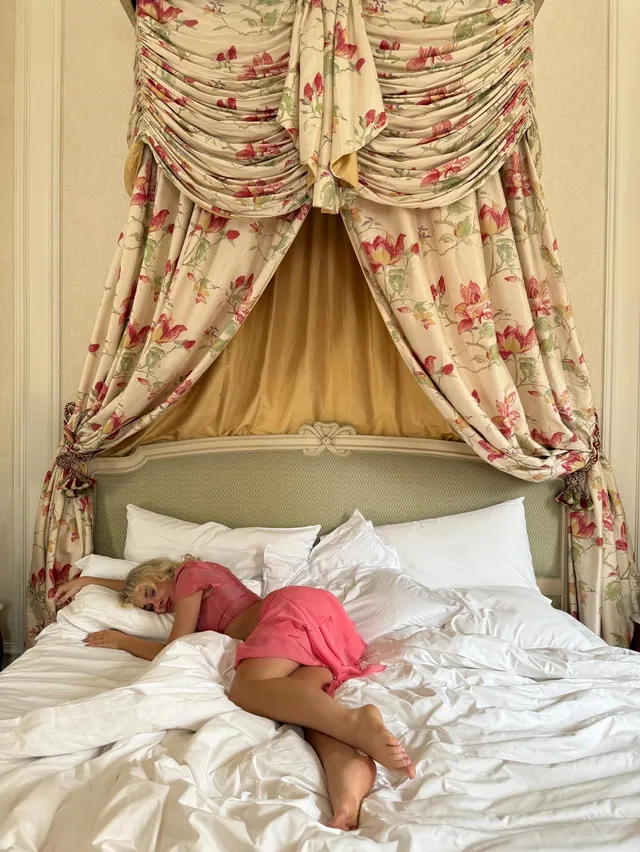 Sabrina Carpenter: reclining barefoot in a pink outfit on a bed.