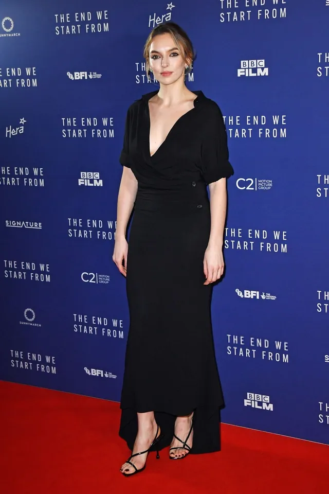 Jodie Comer posing on a red carpet in a long black dress.