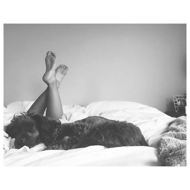 Danielle Campbell lying on a bed for a black-and-white portrait.