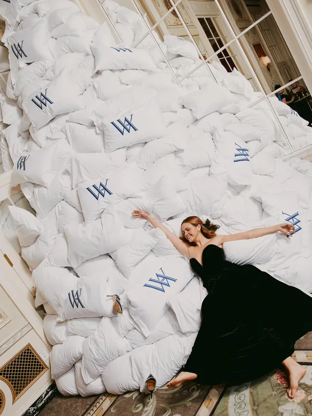 Bailee Madison reclining barefoot beside a large display.