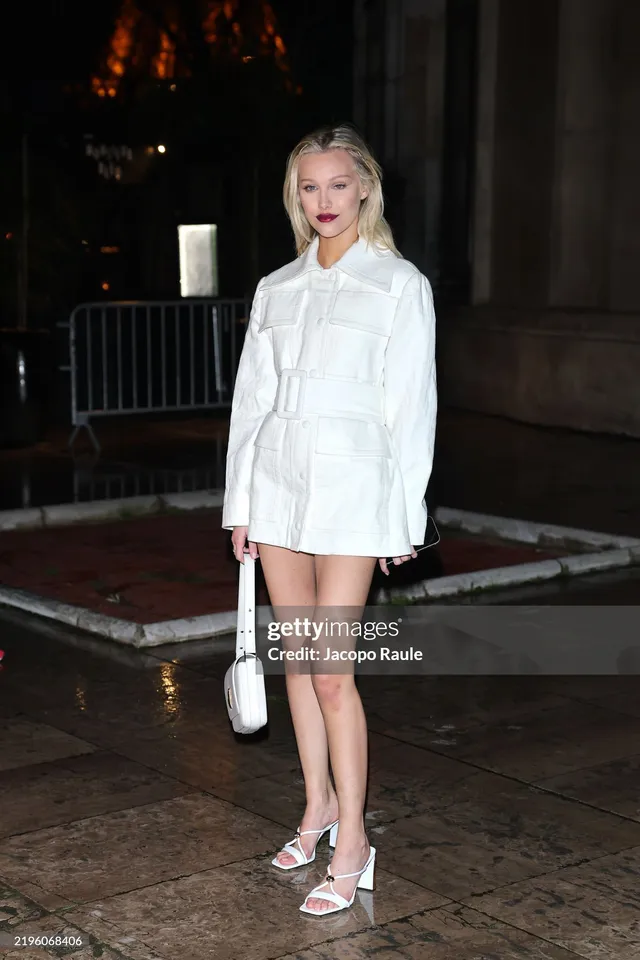 Grace VanderWaal wearing a white mini dress and white heels outside at night.