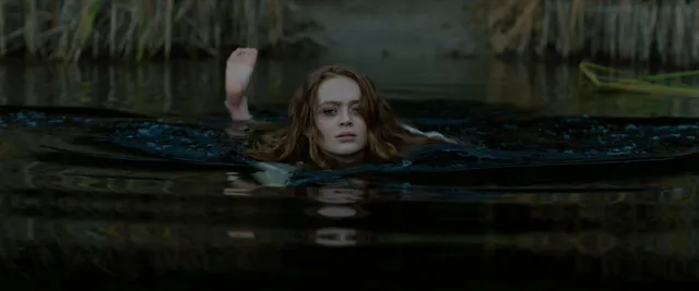 Sadie Sink floating in dark water during a screen scene.