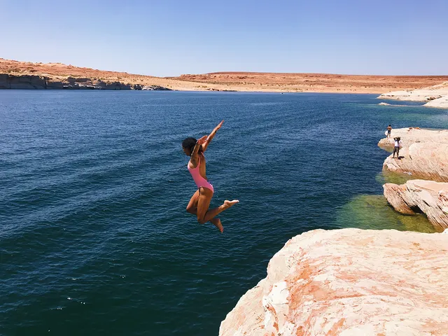 Samantha Logan jumping barefoot from rocks into blue water.