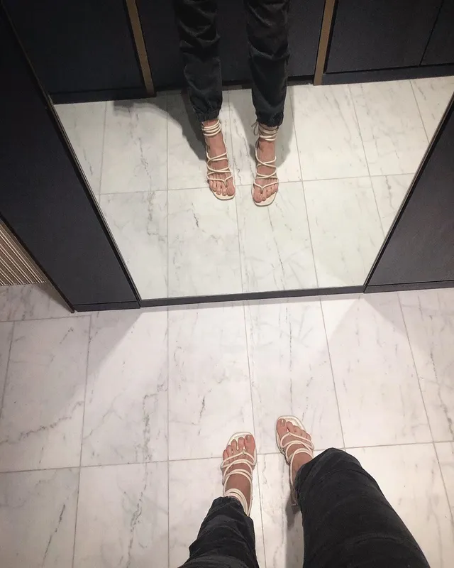 Debby Ryan wearing light-colored strappy sandals in a mirror view.