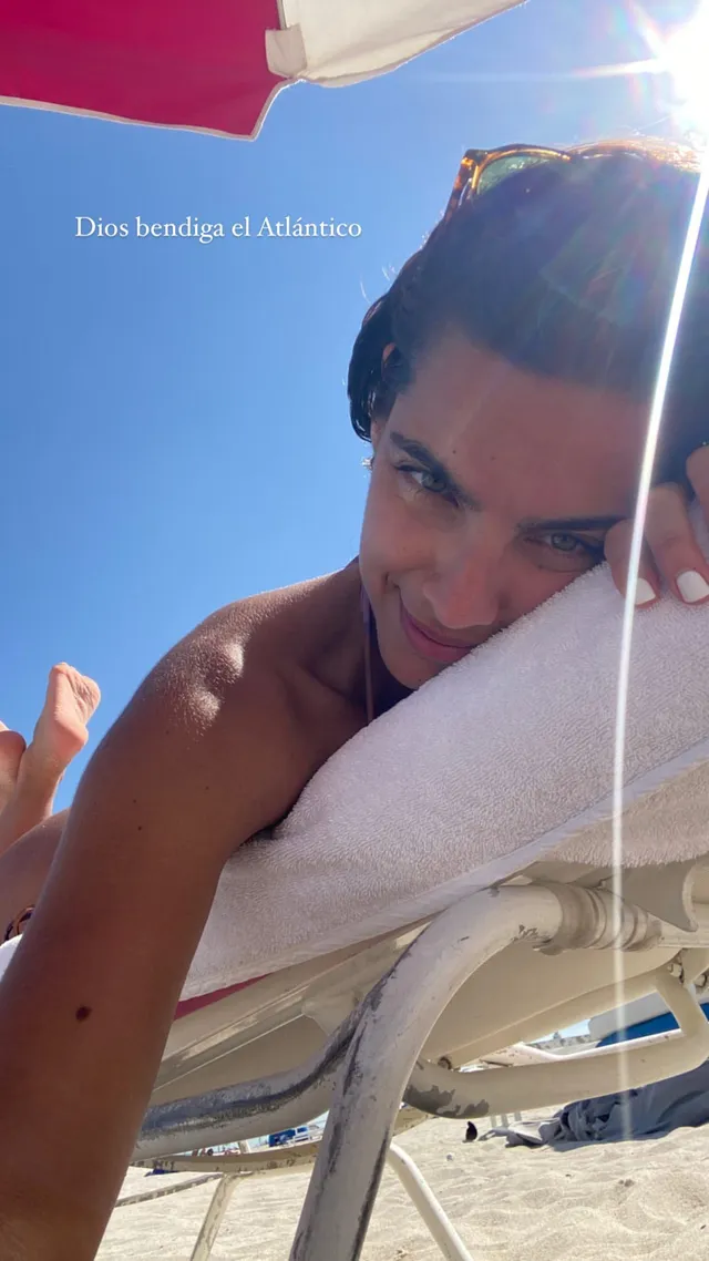 María Gabriela de Faría reclining barefoot on a beach lounger.
