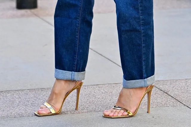 Heidi Klum wearing gold heeled sandals with jeans.