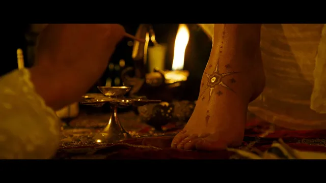 Gemma Arterton standing beside a table in a candlelit screen scene.