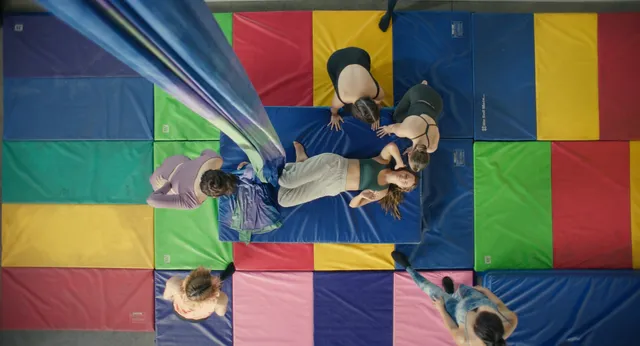 Bailee Madison lying barefoot on a colorful gym mat.