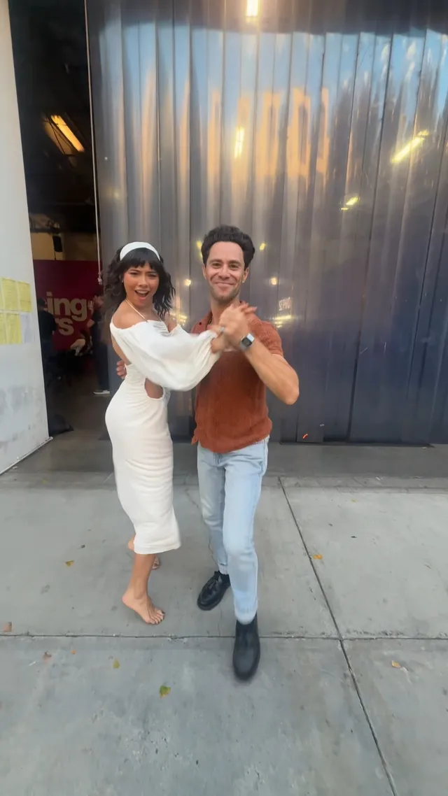 Xochitl Gomez dancing barefoot beside a man outside a building.