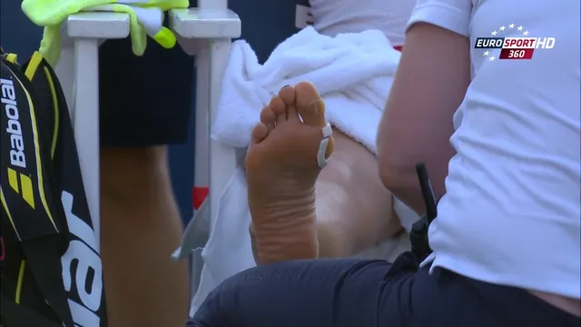 Eugenie Bouchard receiving treatment to her bare sole beside a tennis court.