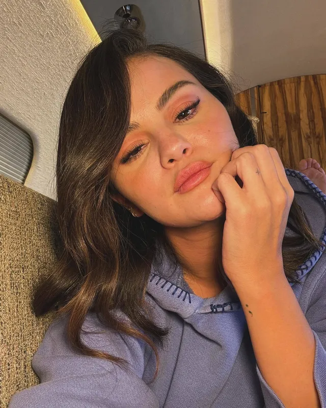 Selena Gomez posing for a close up portrait in a blue shirt.