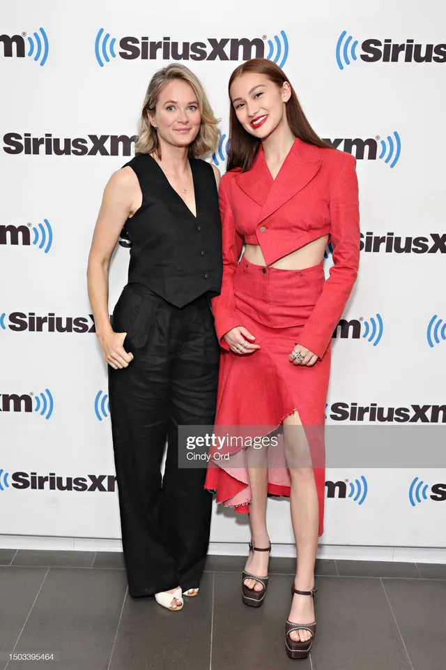 Lola Tung posing with a guest in a red outfit and black heels.