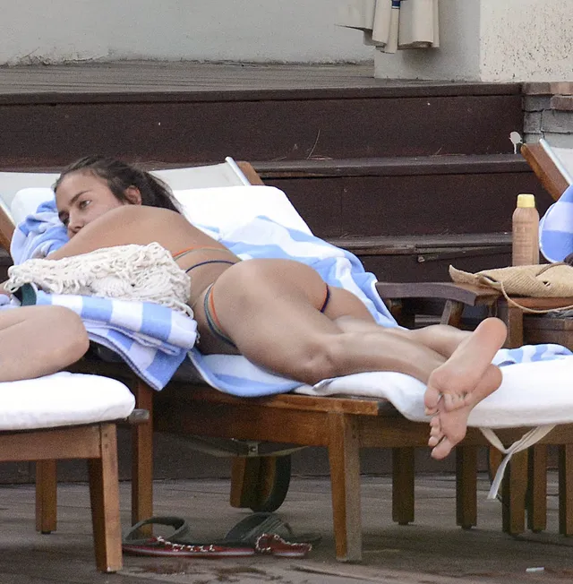 Irina Shayk reclining on a wooden sunbed.